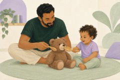 Pai e criança fingem alimentar um urso de pelúcia usando colheres grandes.